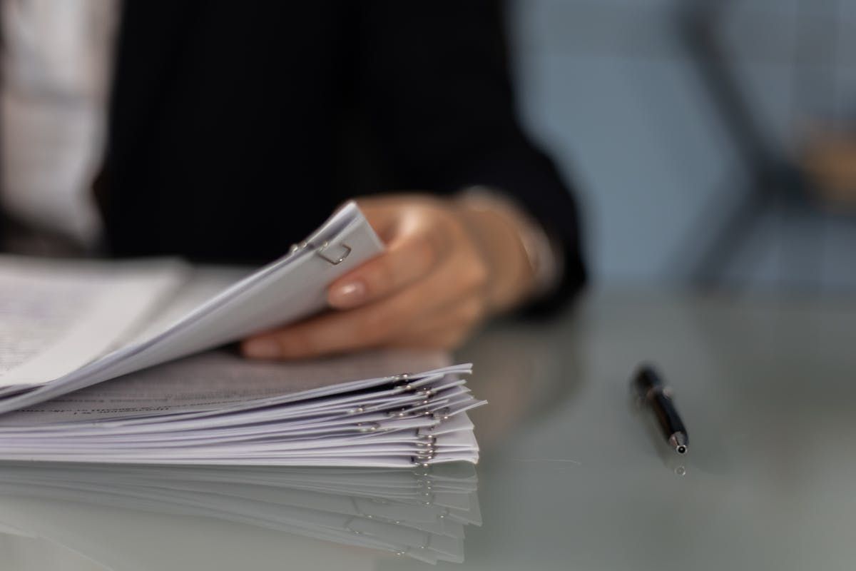 Close-up of a person sorting through a thick stack of legal documents on a desk