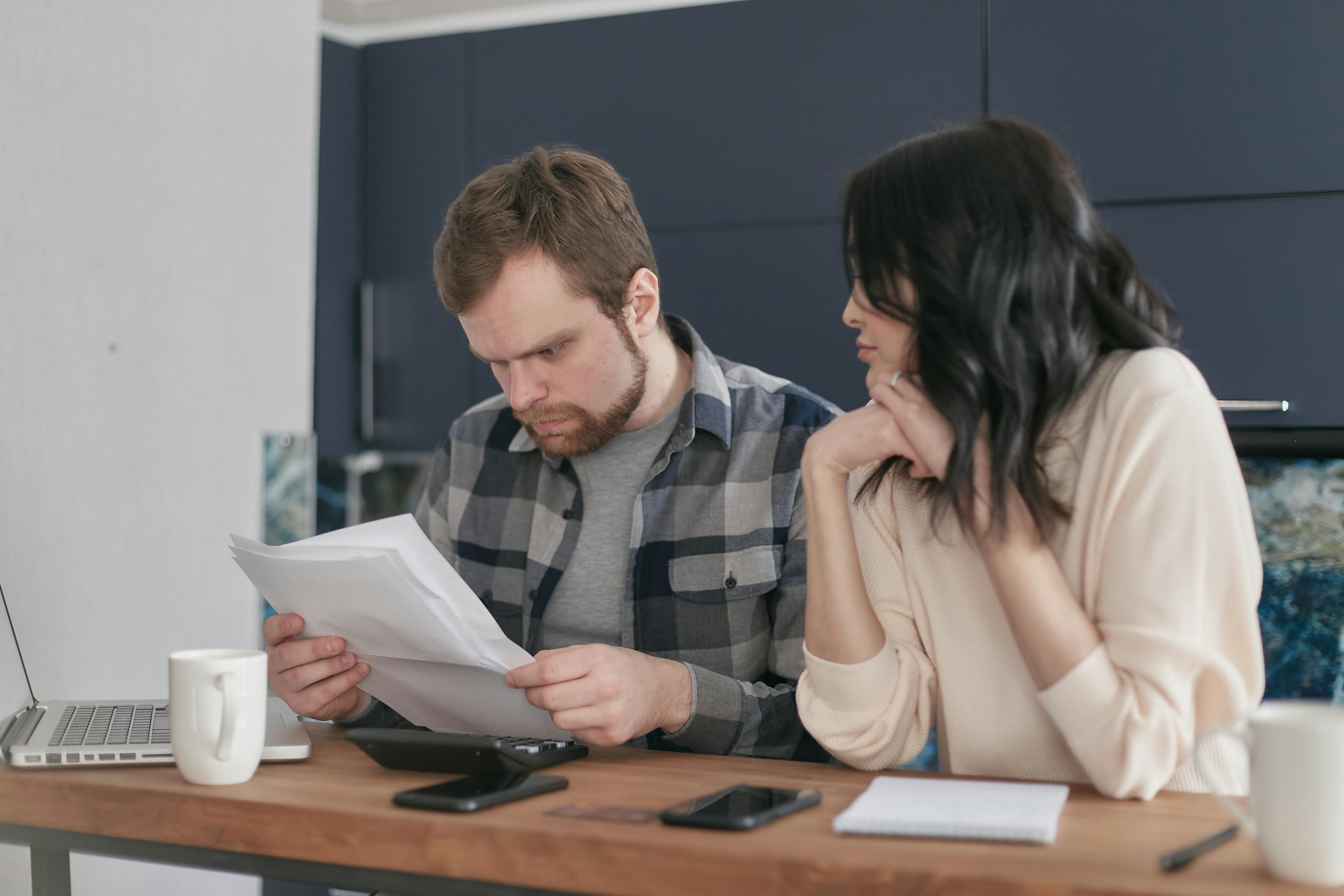 Couple reviewing documents at a table with serious expressions